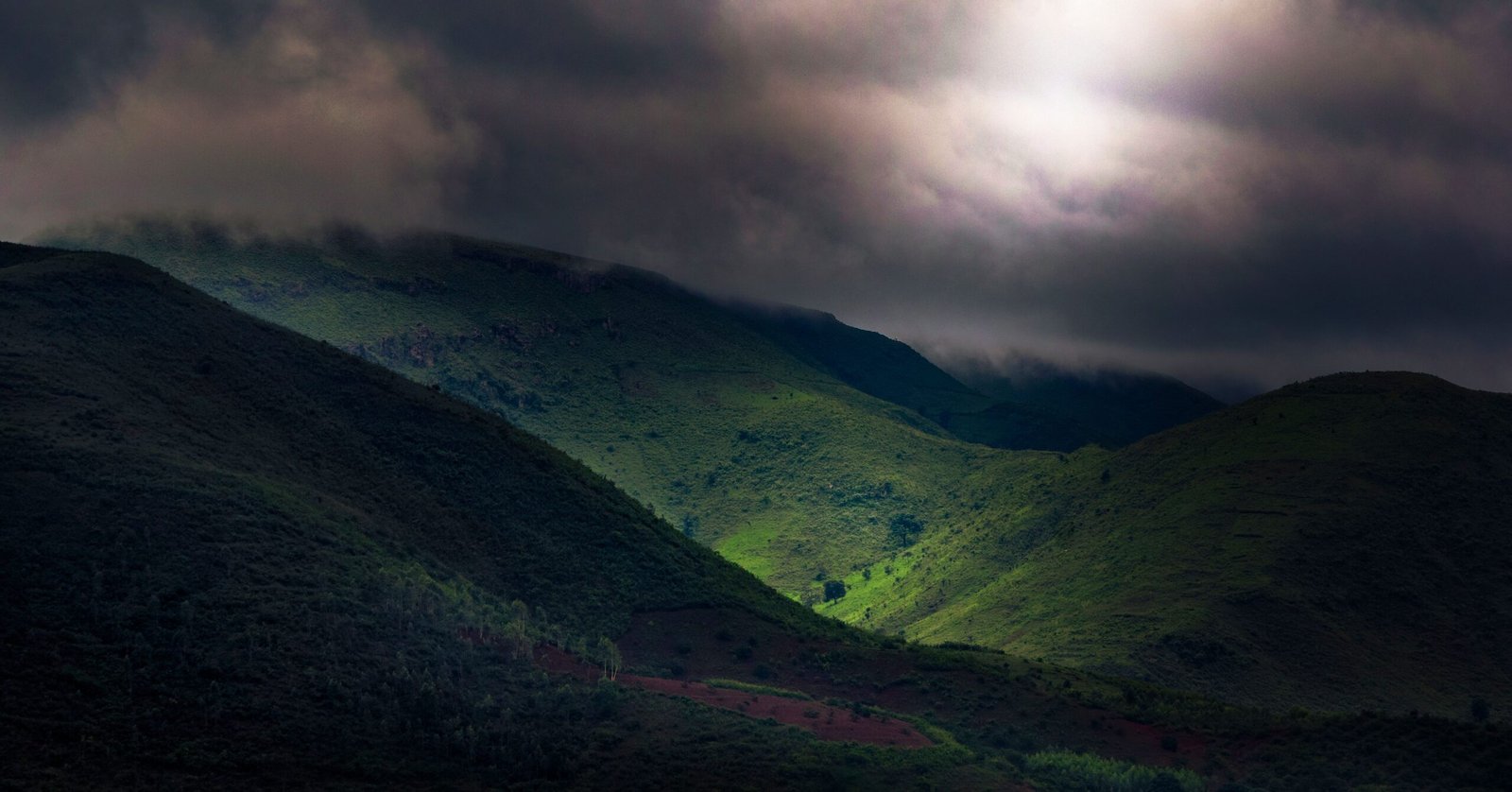 Scenic view of Koraput hills under dramatic clouds, displaying lush greenery and dynamic lighting.